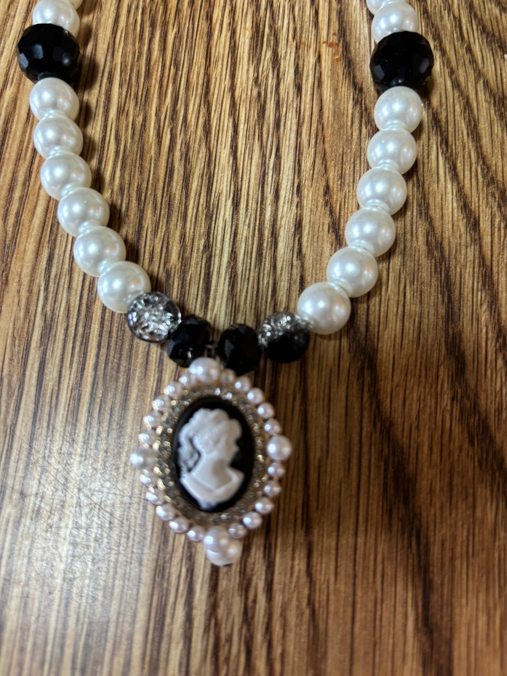 Debutante necklace with white pearl-look beads, black accents and a cameo-style pendant