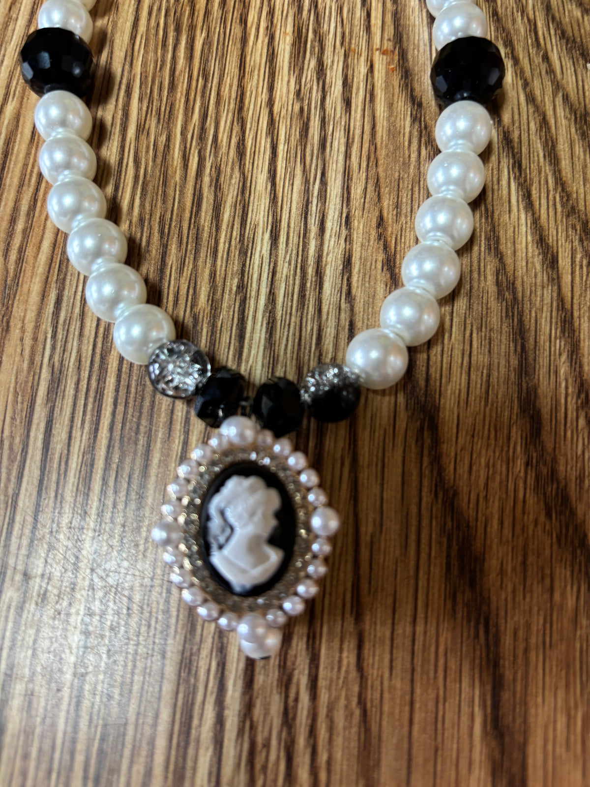 Debutante necklace with white pearl-look beads, black accents and a cameo-style pendant