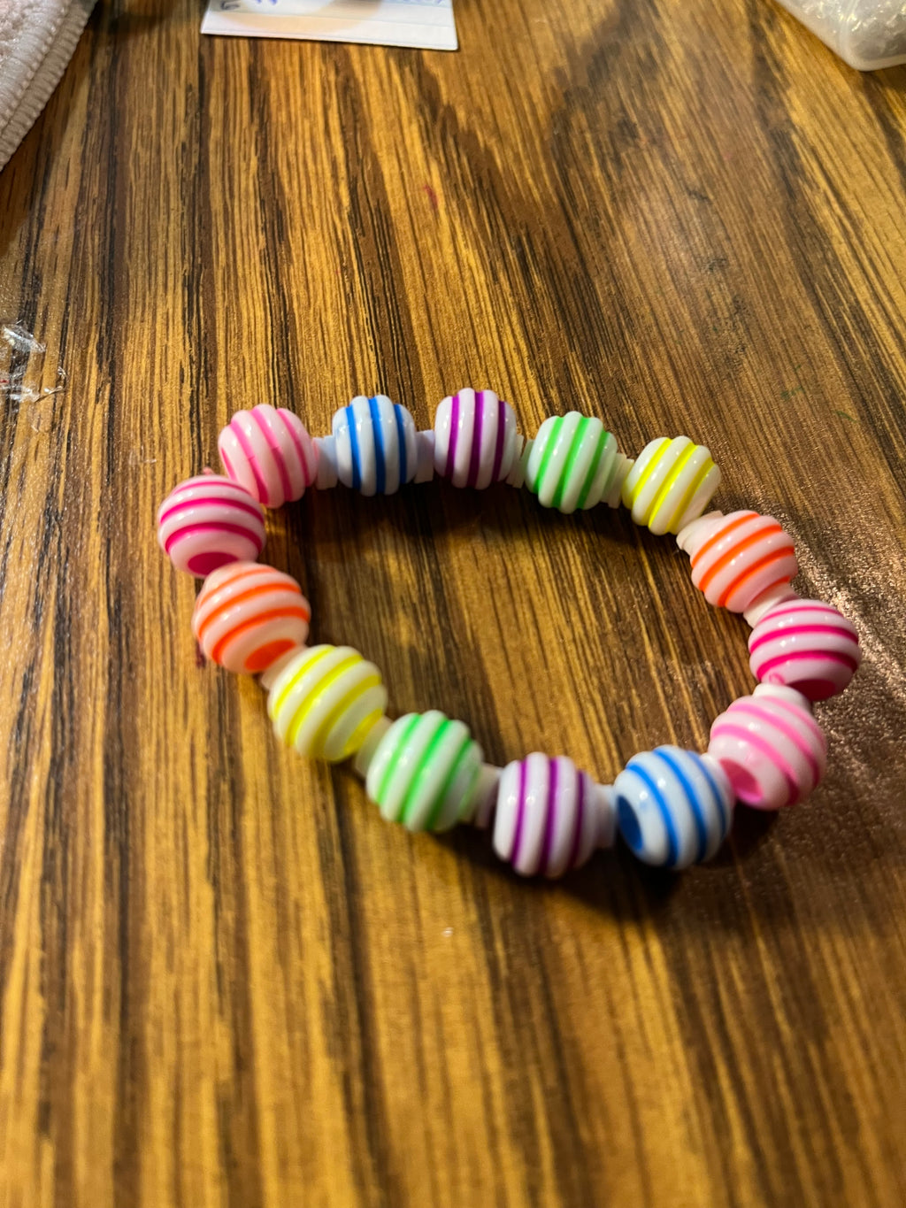Rainbow Taffy colorful striped bead stretch bracelet on wood surface