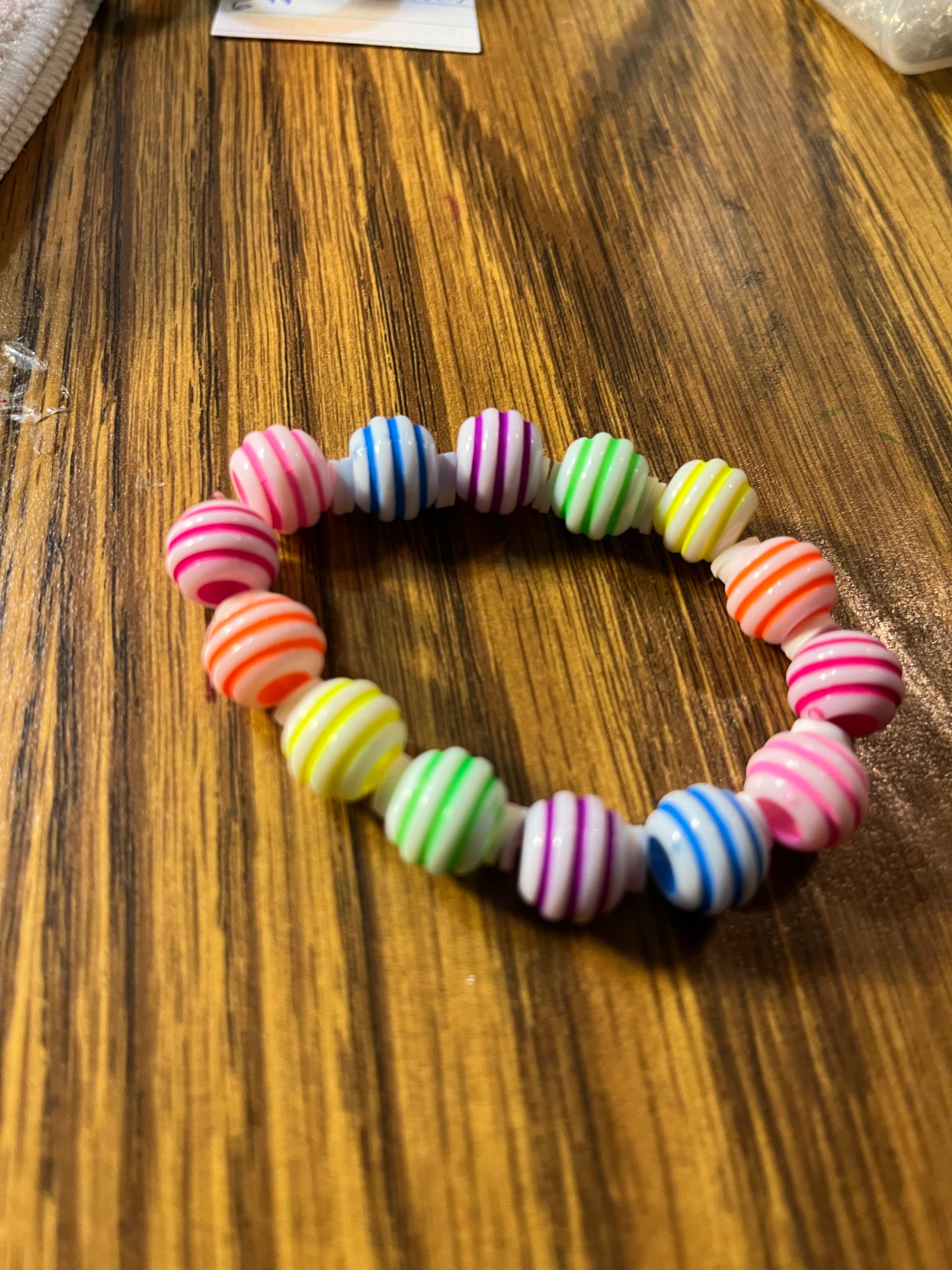Rainbow Taffy colorful striped bead stretch bracelet on wood surface