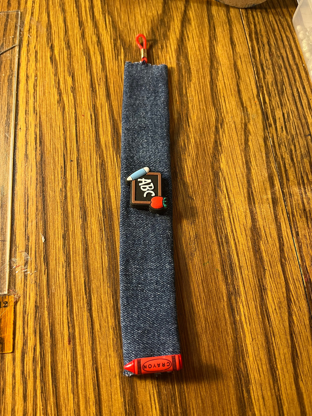 The Basics denim wrist wrap full length showing ABC chalkboard charm and red loop closure