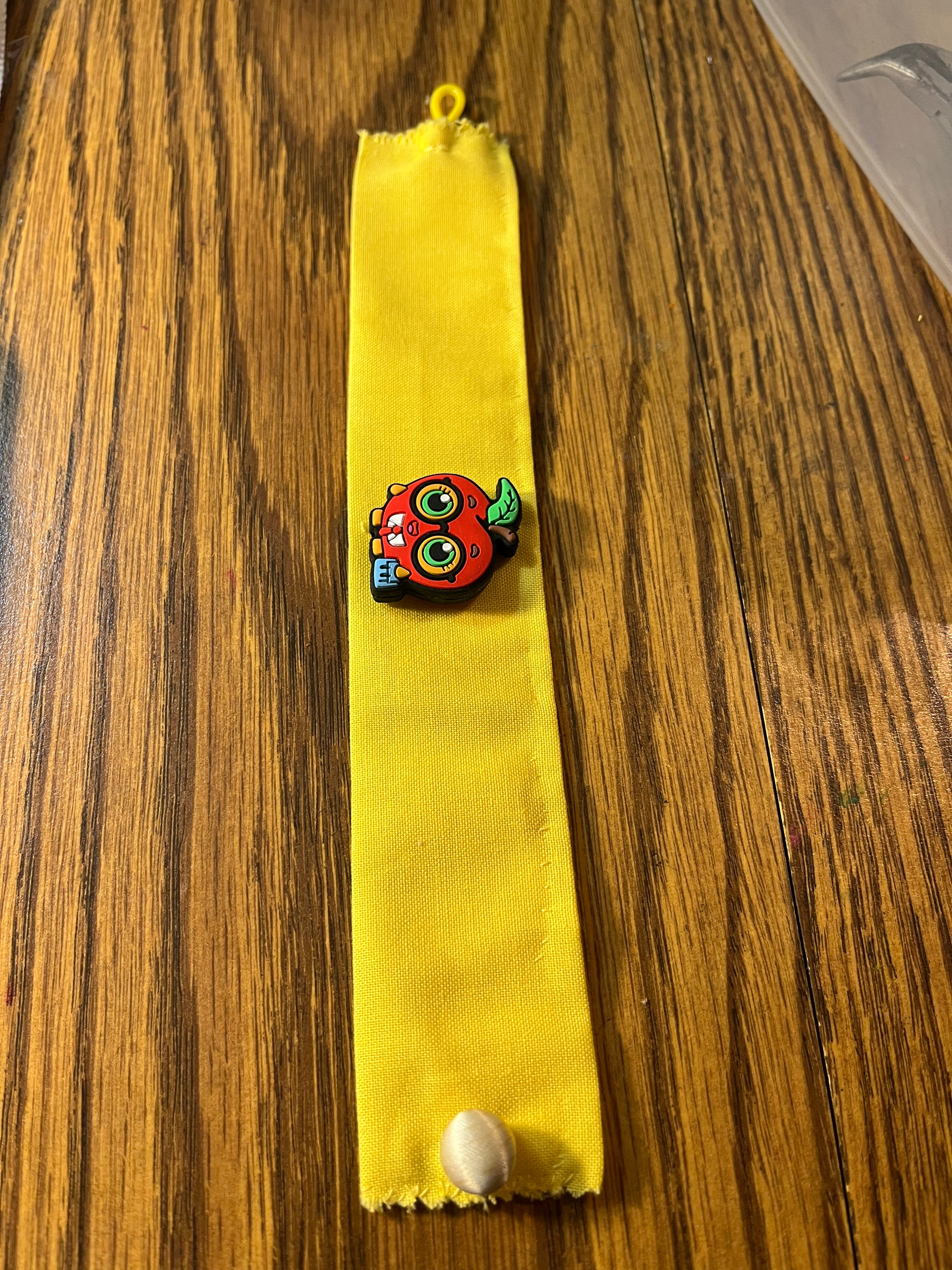 Teacher's Pet yellow wrist wrap full length showing apple charm and loop closure