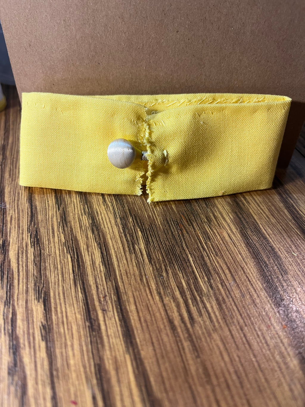 Teacher's Pet yellow wrist wrap close-up showing pearl snap button closure