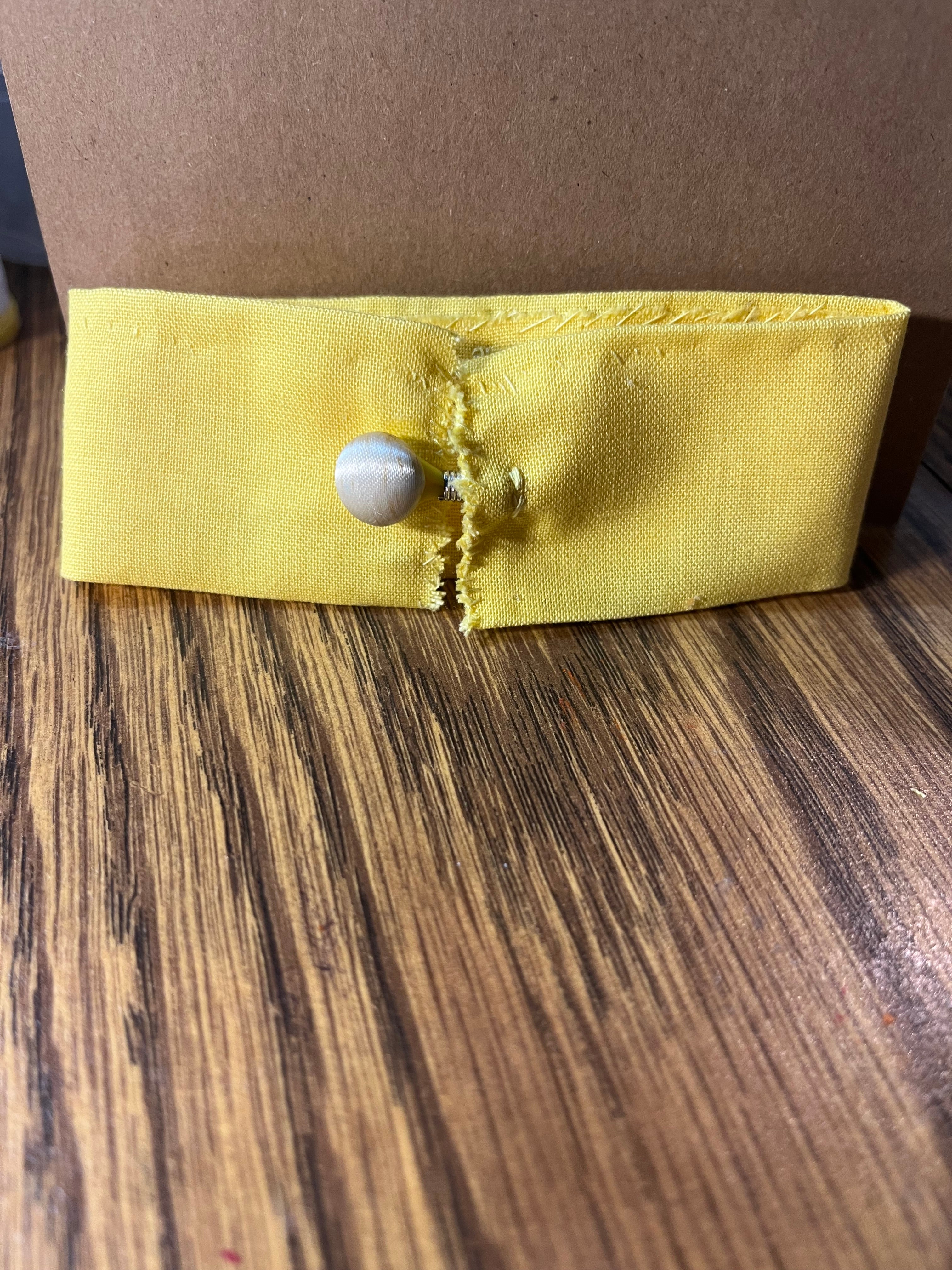 Teacher's Pet yellow wrist wrap close-up showing pearl snap button closure