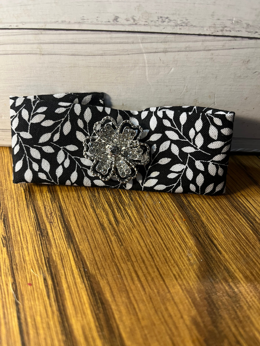 Shimmer & Shine black leaf print wrist wrap folded showing rhinestone flower brooch