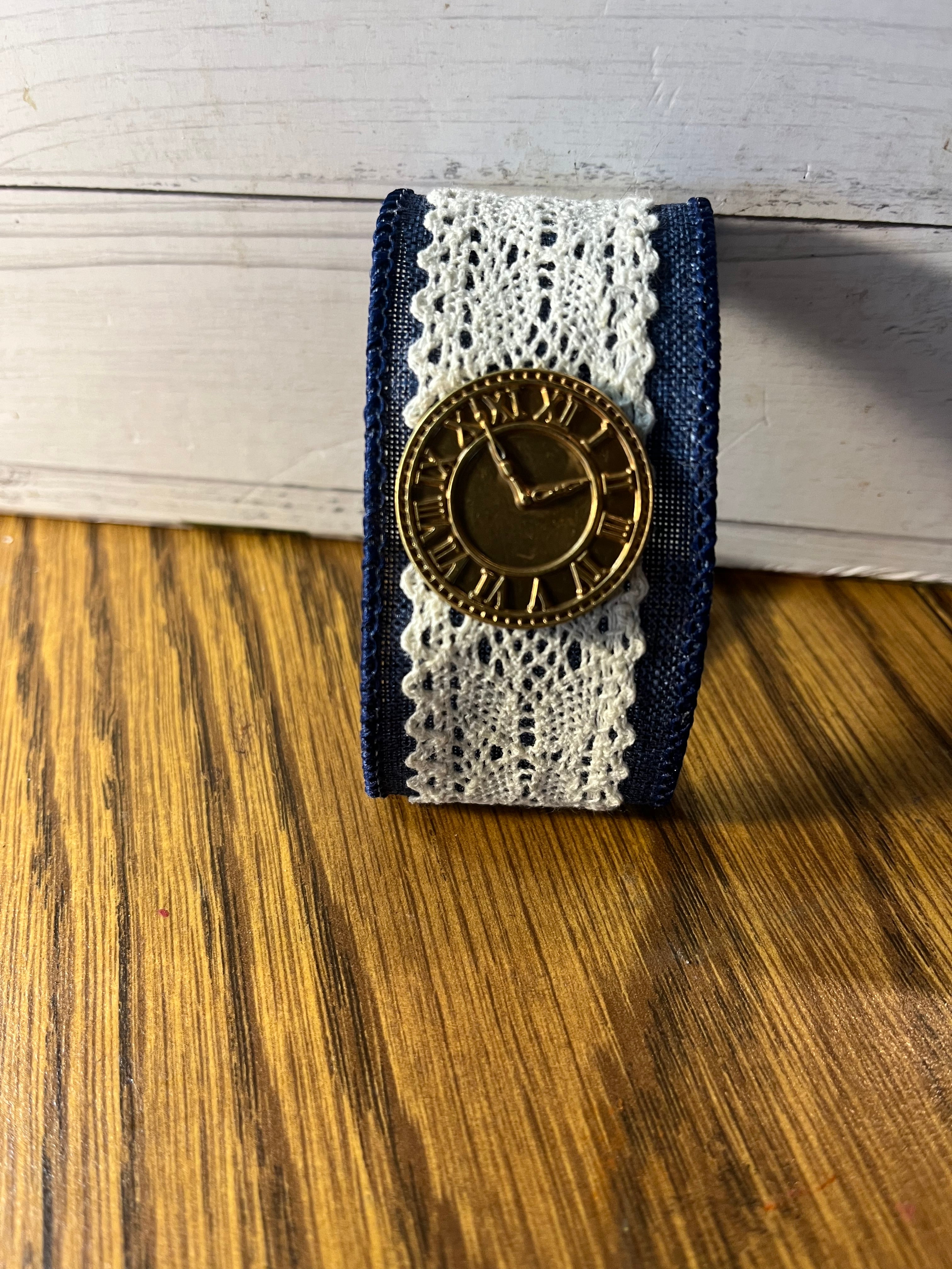 Time Well Spent navy denim and lace wrist wrap folded showing gold clock charm