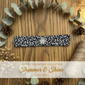Black and white leaf print wrist wrap with silver rhinestone flower brooch on weathered wood