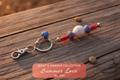 Summer Love beaded keychain with blue heart charm and floral lampwork beads on driftwood surface