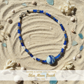 Cobalt blue crackle glass beaded necklace with moon charms and art glass focal bead on sand surface