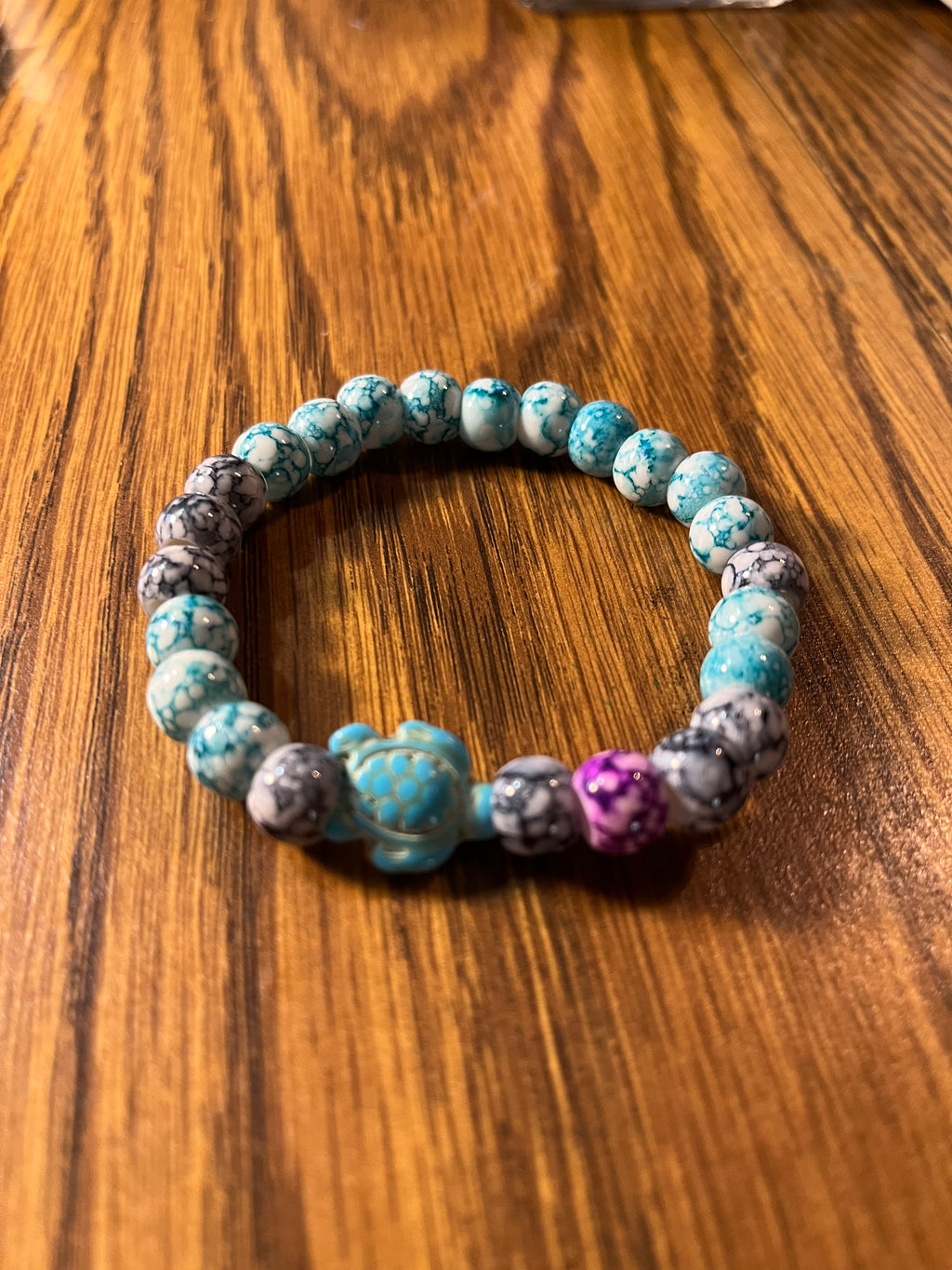 Turtle Tide teal marbled bracelet showing purple accent bead and sea turtle charm